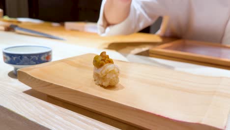 chef places sushi on wooden serving board