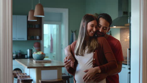 Pregnant,-dancing-and-happy-couple-in-a-kitchen