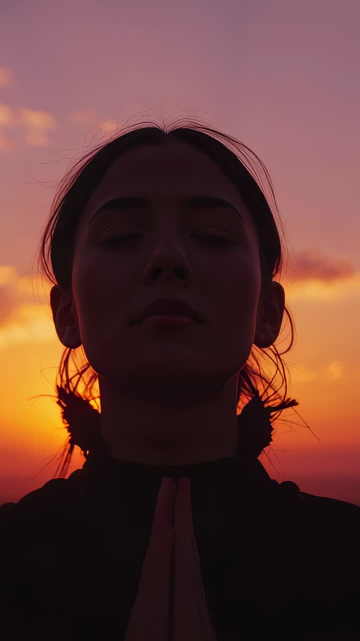 Vertical video: Holding hands, woman in high collar lifting head while sun sets, meditating smiling