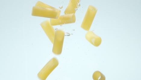los cannelloni secos de pasta caen bajo el agua con burbujas de aire.