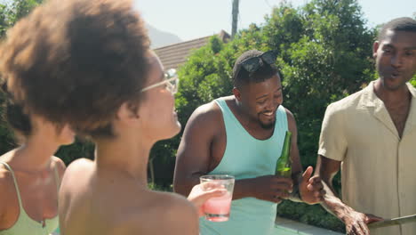 diverse friends enjoying sunny day by pool, laughing and holding drinks outdoors