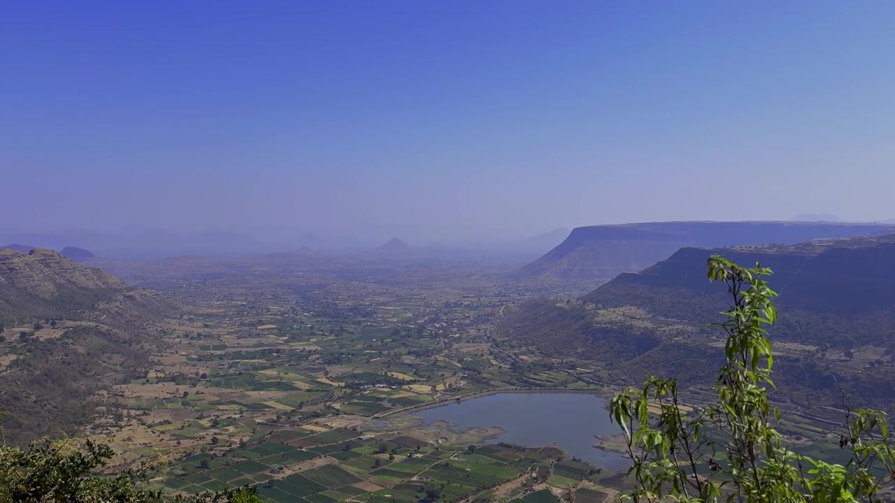 Vista panoramica suggestiva che si affaccia sulla valle, sui terreni agricoli, sul bacino idrico e sulle colline circostanti da un punto panoramico in cima a una collina vicino a Vani, a Nashik, Maharashtra, India