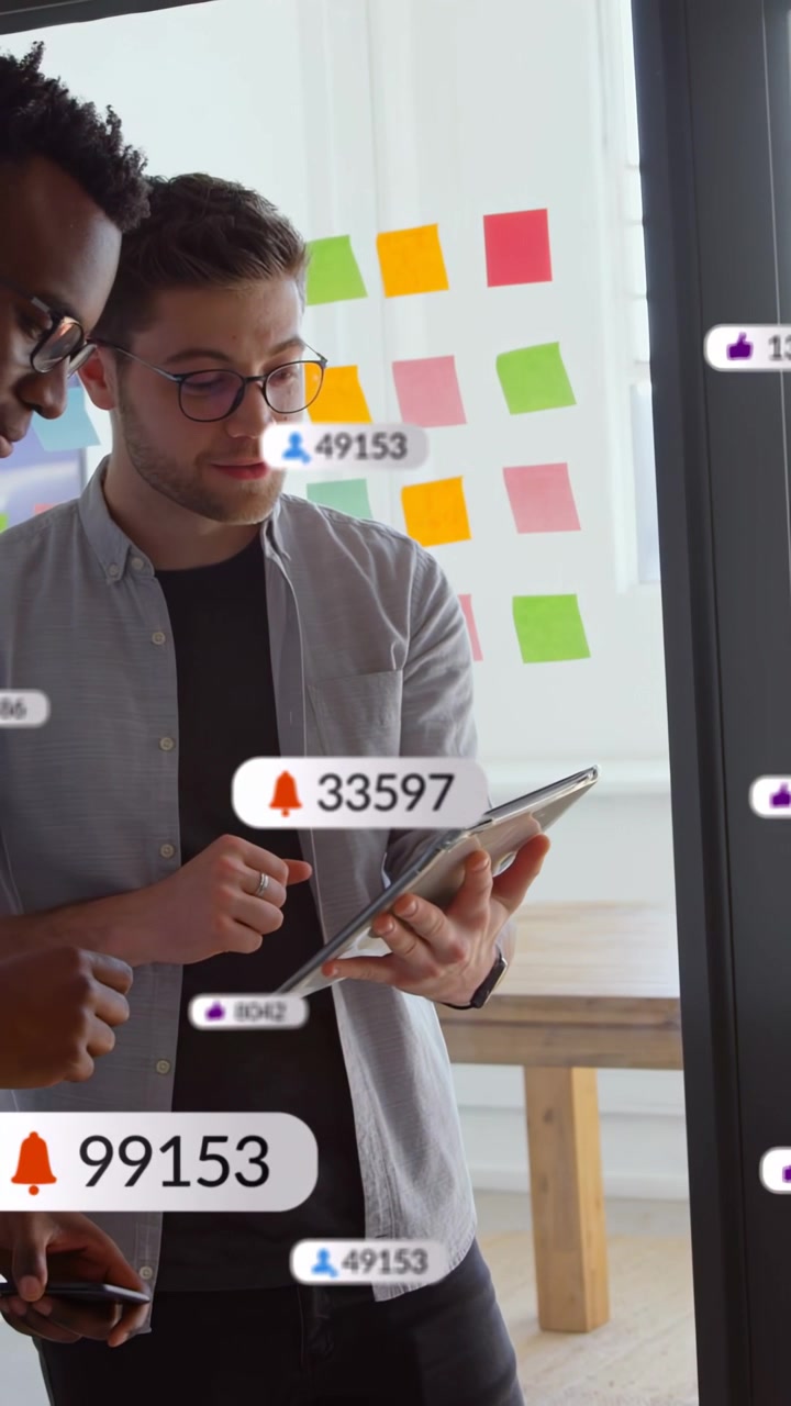 Two men tapping tablet, causing animated bell and like counters, reviewing marketing KPIs, smiling