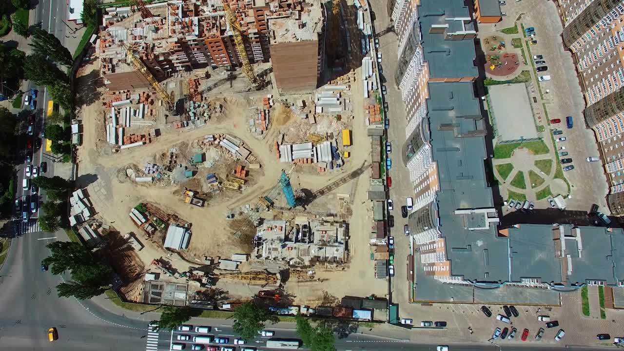 Top aerial view of a construction site in the city. View from above on roofs of newly built high-rise flats next to the construction works. Urban background.