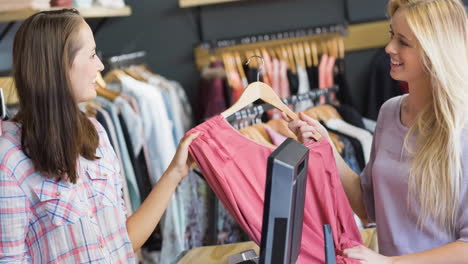 two caucasian women smiling holding t shirt buying clothes in shop