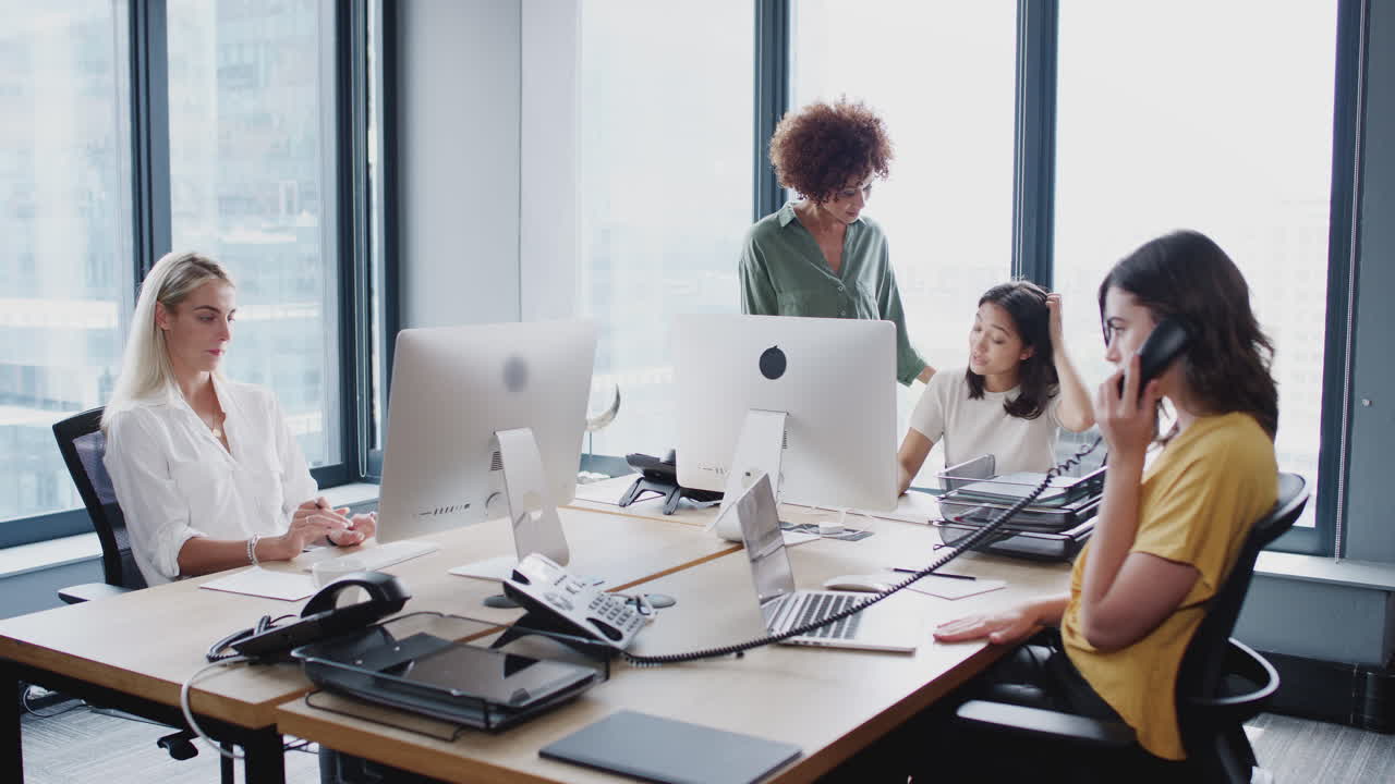 Sort millennial kvinde går rundt på et kontor og taler med sine kvindelige kreative kolleger, fast optagelse.