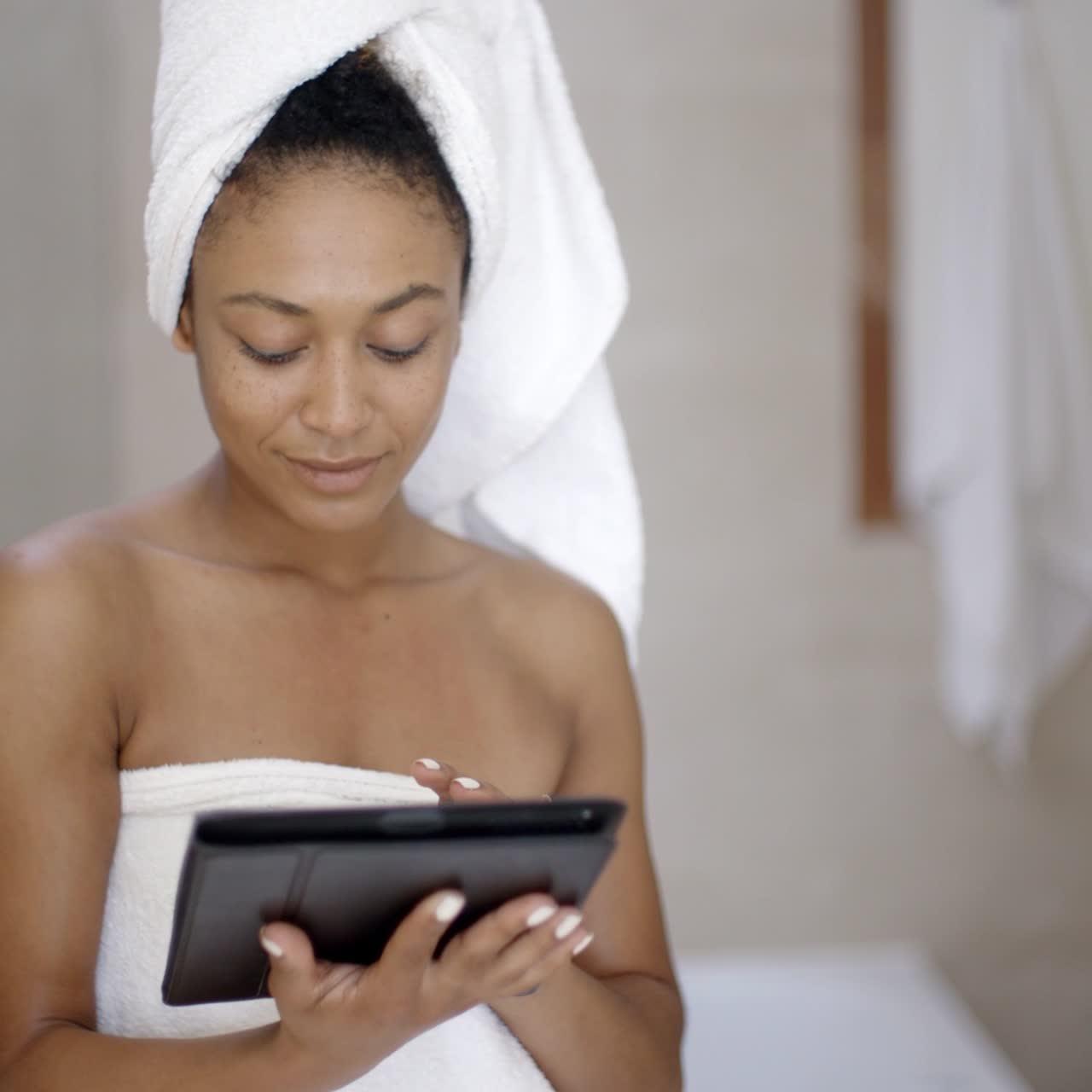 Giovane donna con asciugamano da bagno che usa un tablet