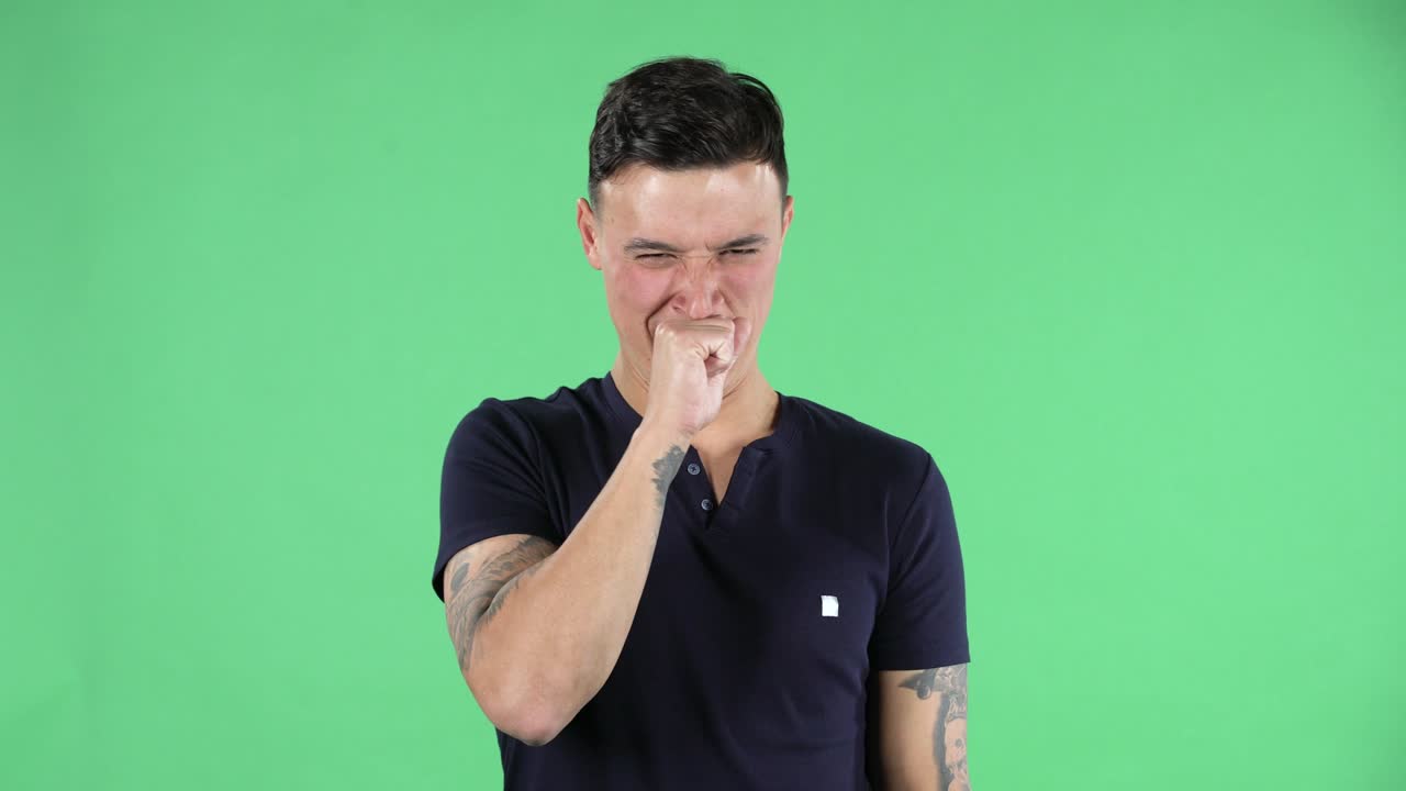 Ritratto di un bel ragazzo che guarda la telecamera e mostra disgusto per un cattivo odore o sapore. Green screen