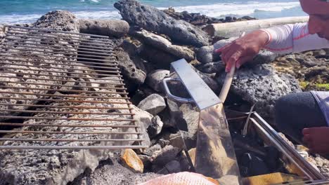 hombre haciendo fuego para barbacoa a la parrilla comida de pescado a la playa frente al mar del caribe