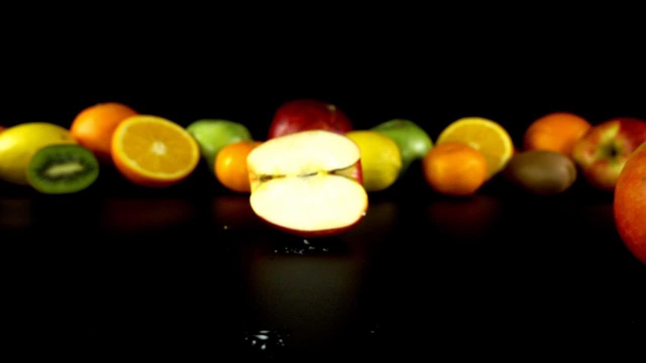 Mela che cade su uno sfondo di frutta. Slow motion