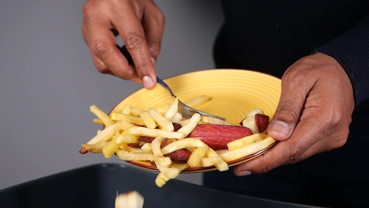 Pessoa Raspando Restos de Comida do Prato para a Lixeira