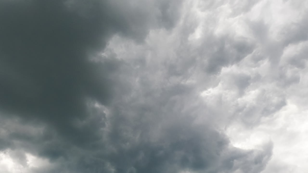 Soft light clouds transform quickly into the grey ones. Low angle view at the storm formation in the atmosphere. Timelapse.