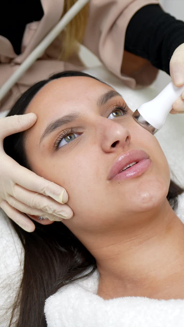 Mujer joven recibiendo un tratamiento facial profesional para el cuidado de la piel
