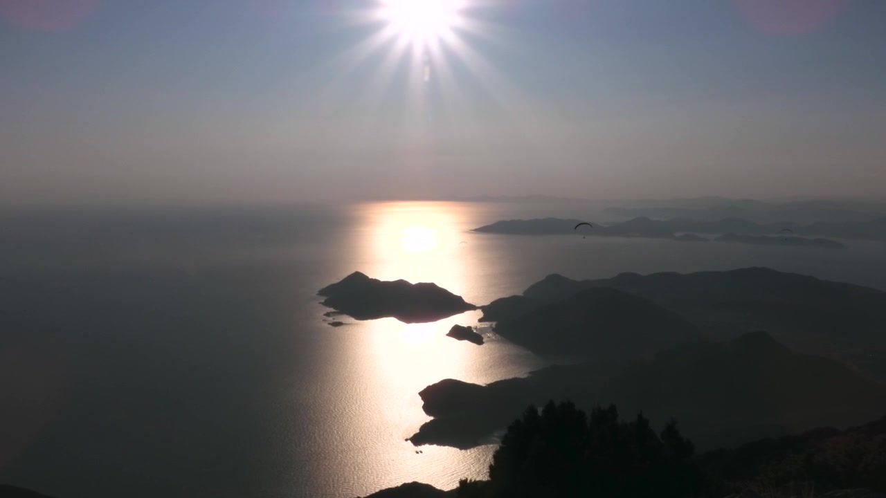 夕暮れの海岸山脈を飛ぶパラグライダー