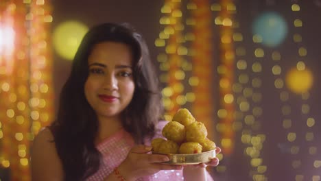 retrato de una mujer celebrando el festival de diwali sosteniendo un plato de ladoo