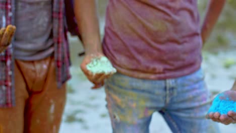 close up of the hands palms of young mixed races people friends holding colorful paints in powder at the holi fest celebration