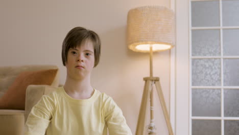 adolescente haciendo yoga y mirando la cámara en casa