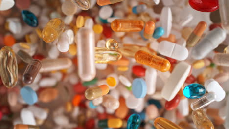 suplementos coloridos y medicamentos vuelan hacia la cámara en cámara lenta, vista superior, macro