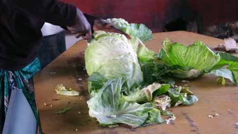 person chopping fresh cabbage on a wooden table in a rustic kitchen