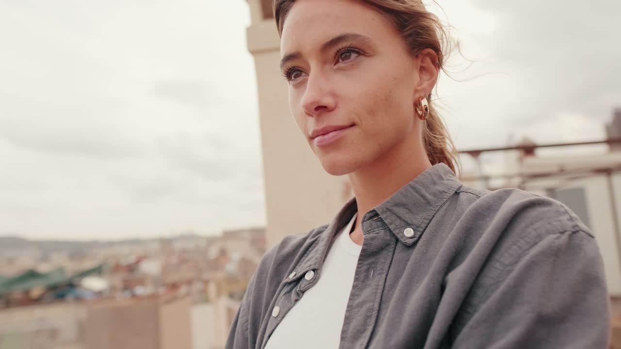 Giovane donna che guarda pensierosa la città da una terrazza