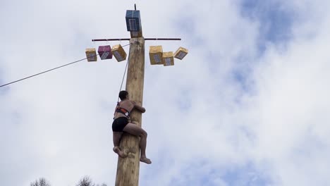 un homme grimpant sur un poteau de bois