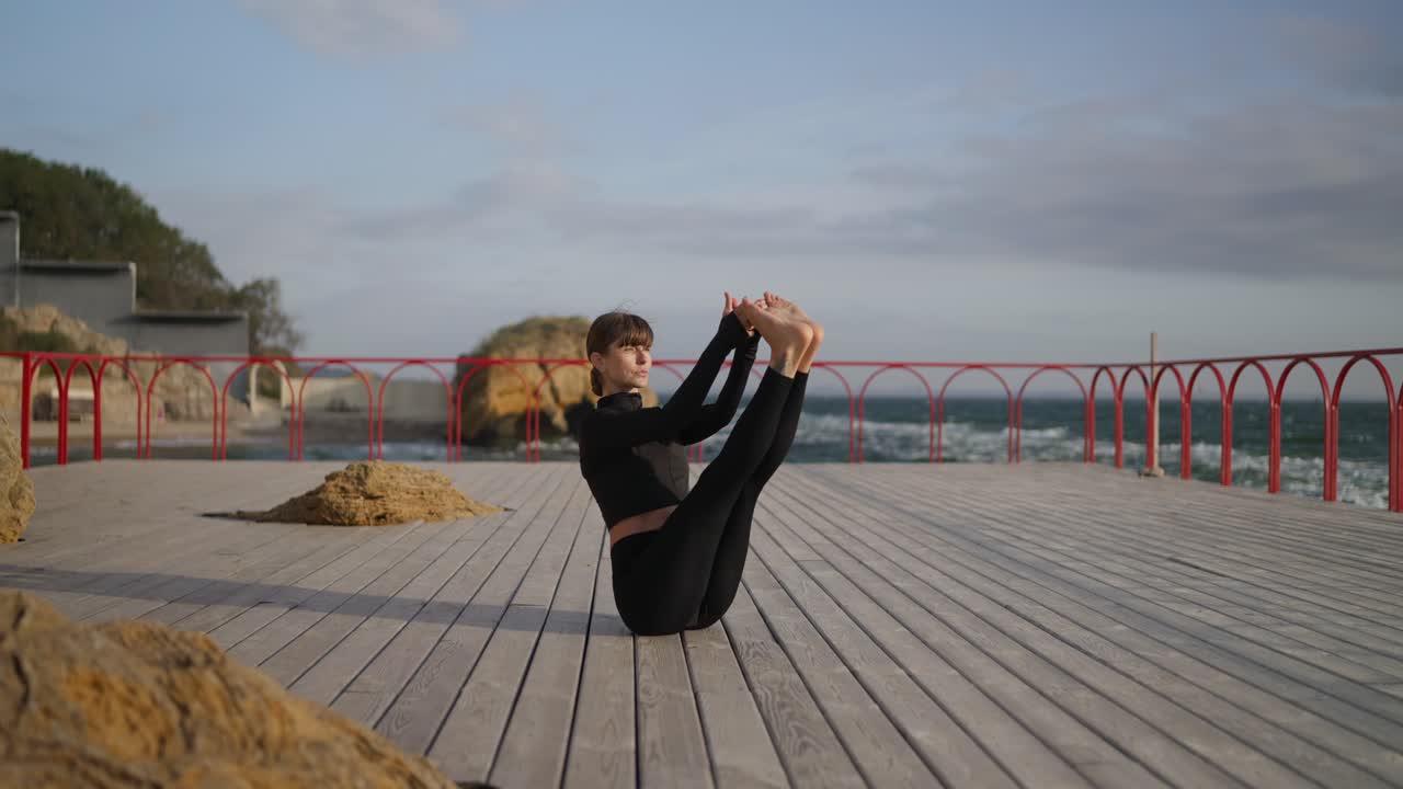 женщина практикует йогу на пирсе.