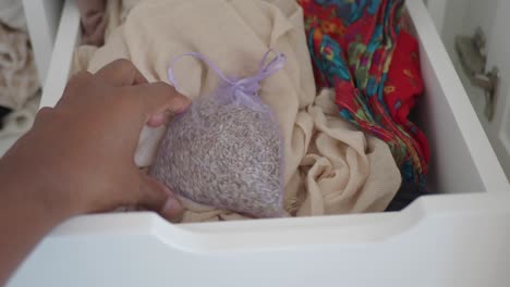 persona que organiza un cajón con ropa y una bolsa de lavanda