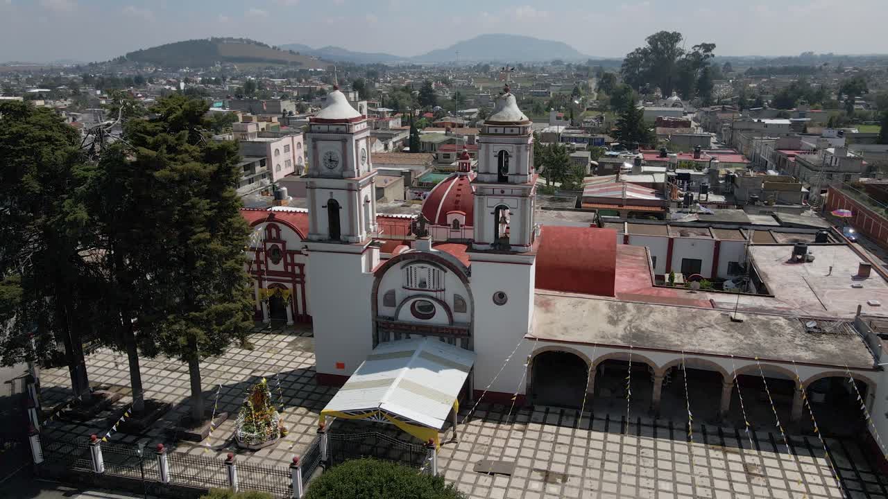 volando sobre una plaza ajardinada hacia las campanas de la iglesia en jalisco almoloya