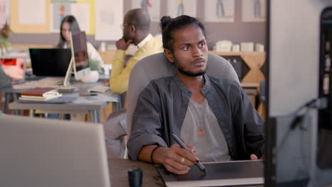 male graphic designer using digital drawing tablet and looking at computer monitor in an animation studio 1