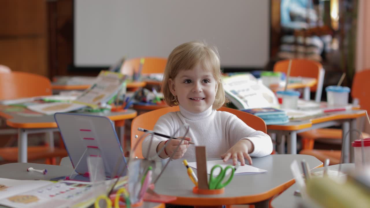 Girl drawing at the table in classroom. Education. Child sitting at a desk
