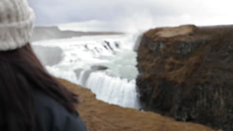 avanzando más allá de la chica mirando la cascada de islandia en cámara lenta