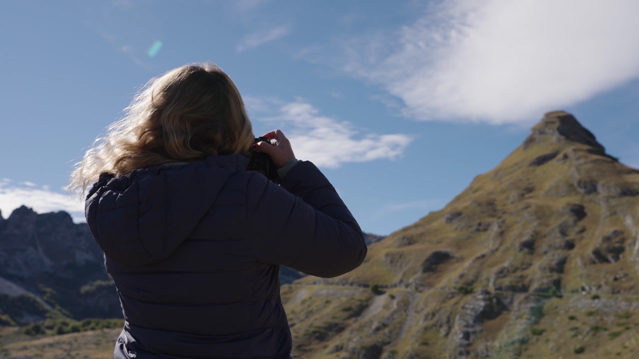 Blonde caucasian tourist taking a picture in the Durmitor massif during the day in Montenegro, static shot