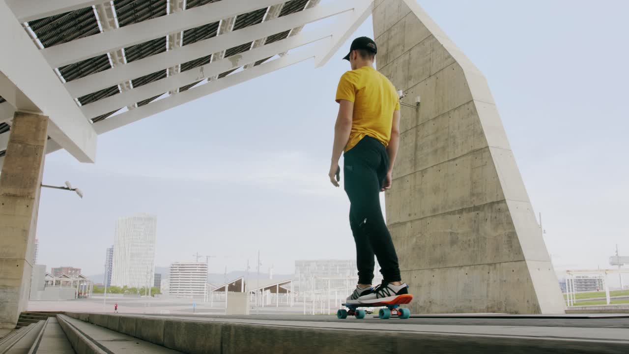 Young Attractive Trendy Man skateboarding fast under a solar panel on a morning sunny day with an urban city background in slow motion