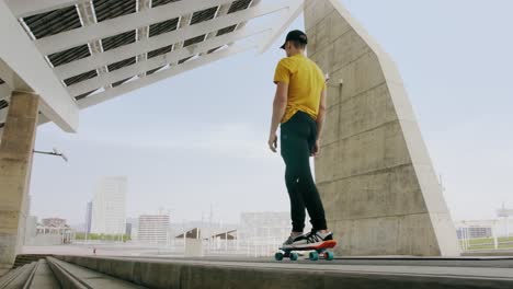 young attractive trendy man skateboarding fast under a solar panel on a morning sunny day with an urban city background in slow motion