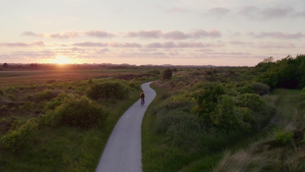 Vista do pôr do sol em Terschelling com ciclista no caminho, Frísia, Países Baixos