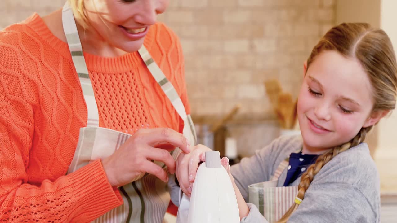 madre y hija sonrientes mezclando mezcla con batidora electrónica en la cocina 4k 4k