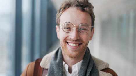 close-up of the face of a young blond guy with glasses smiling at the camera