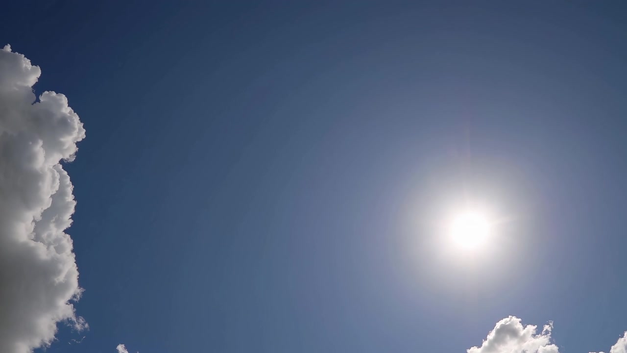 Klar sol der skinner på en klar blå himmel med bløde skyer