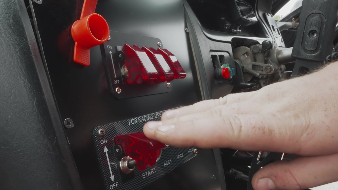 Hand betätigt Schalter am Bedienfeld eines Rennwagens und den Motorstartknopf