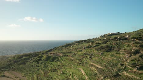 aerial: car driving up to hill near mediterranean sea on a sunny evening in malta