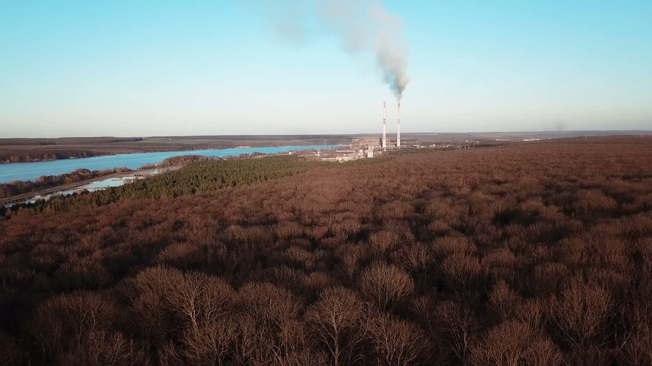 power plant is operating near the forest and the river in the autumn. Aerial view