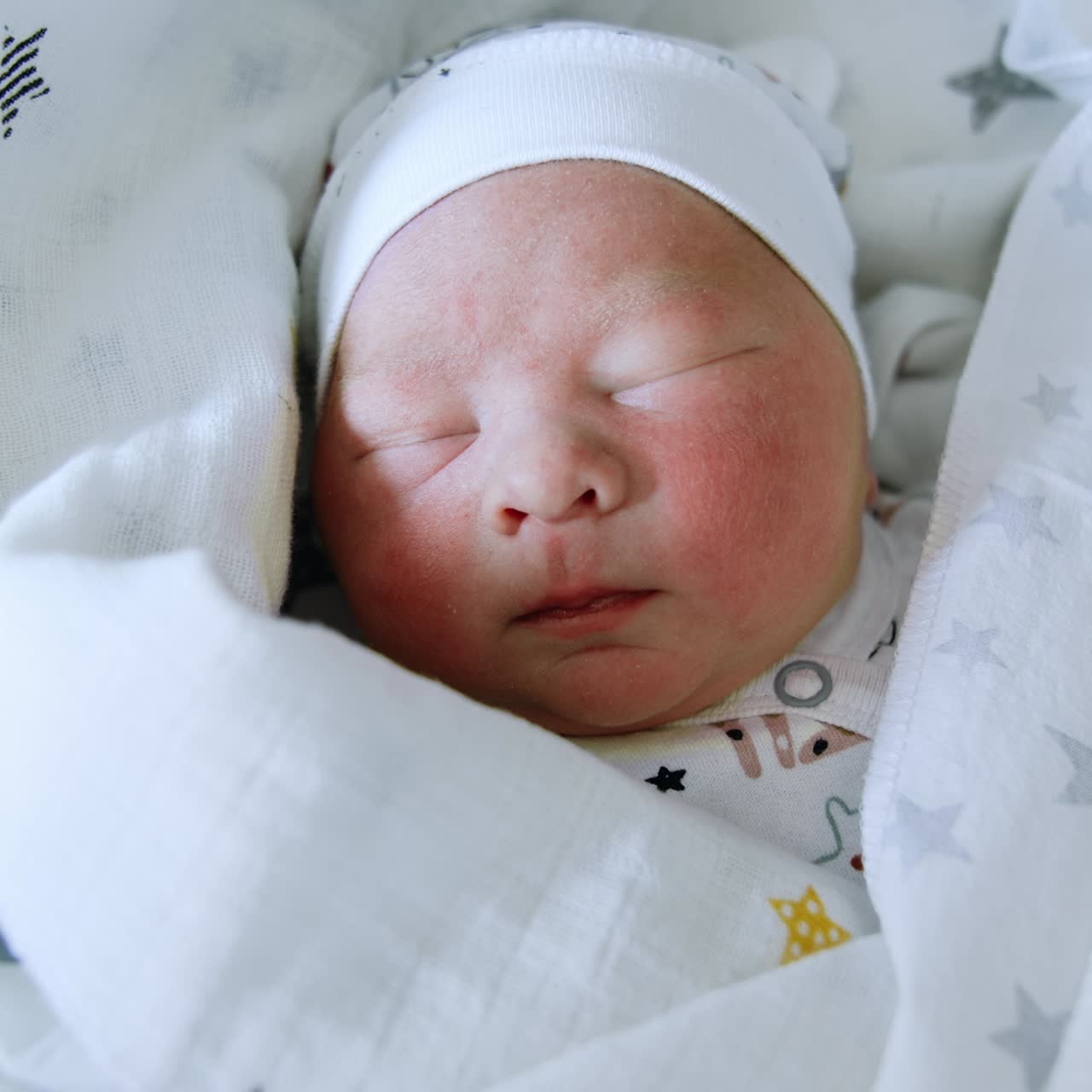 Un adorabile neonato che dorme con un cappellino e coperto da coperte. Primo piano di neonato. Sfondo giallo