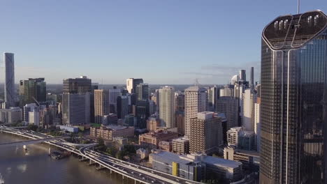 aerial lowering shot of motorway with cars passing at base of building along river brisbane, queensland