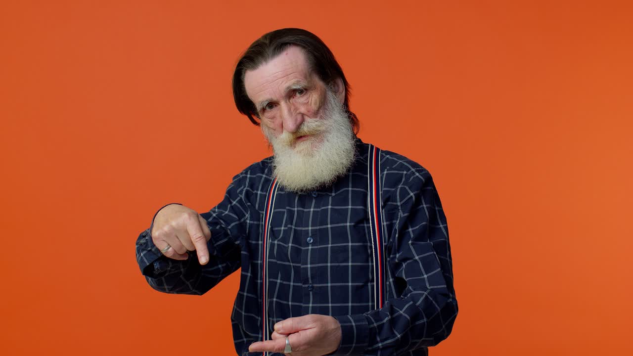Anziano uomo barbuto e dai capelli grigi che guarda la telecamera facendo il gesto del telefono, come a dire "ehi, richiamami".