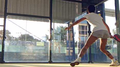 mujer jugando padel devuelve la pelota de la pared trasera de la cancha