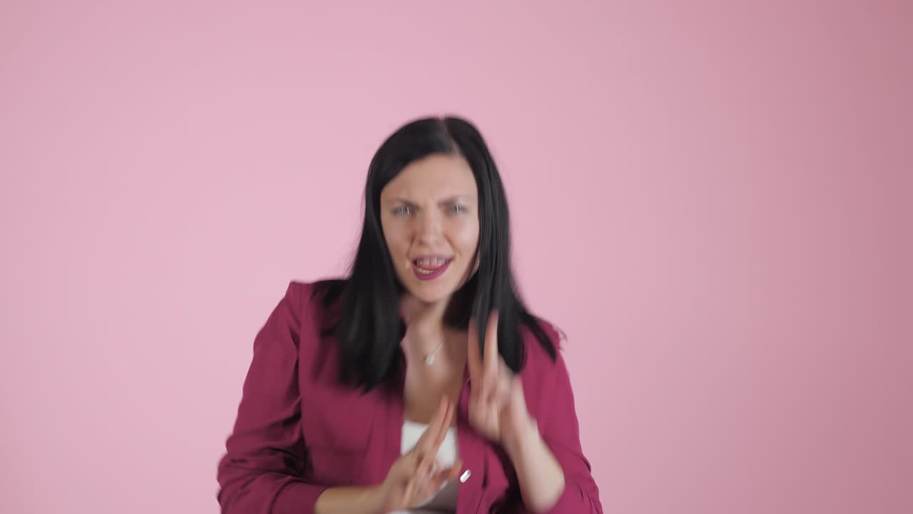 niña de energía en fondo rosa en el estudio. ella lleva una camisa de colores. cabello negro en la cola está volando de movimiento. 4k