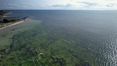 kitesurfistas en el tranquilo océano verdoso: vista aérea de drones