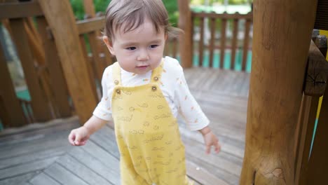 adorable korean-ukrainian multi-ethnic asian toddler girl playing on a wooden playground - isolated close up in slow motion