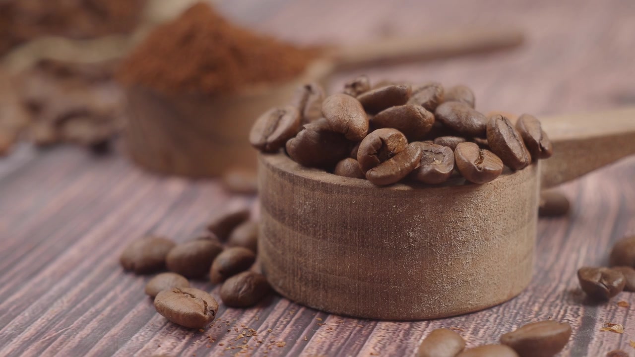 Chicchi di caffè tostati in un mestolo di legno con caffè macinato