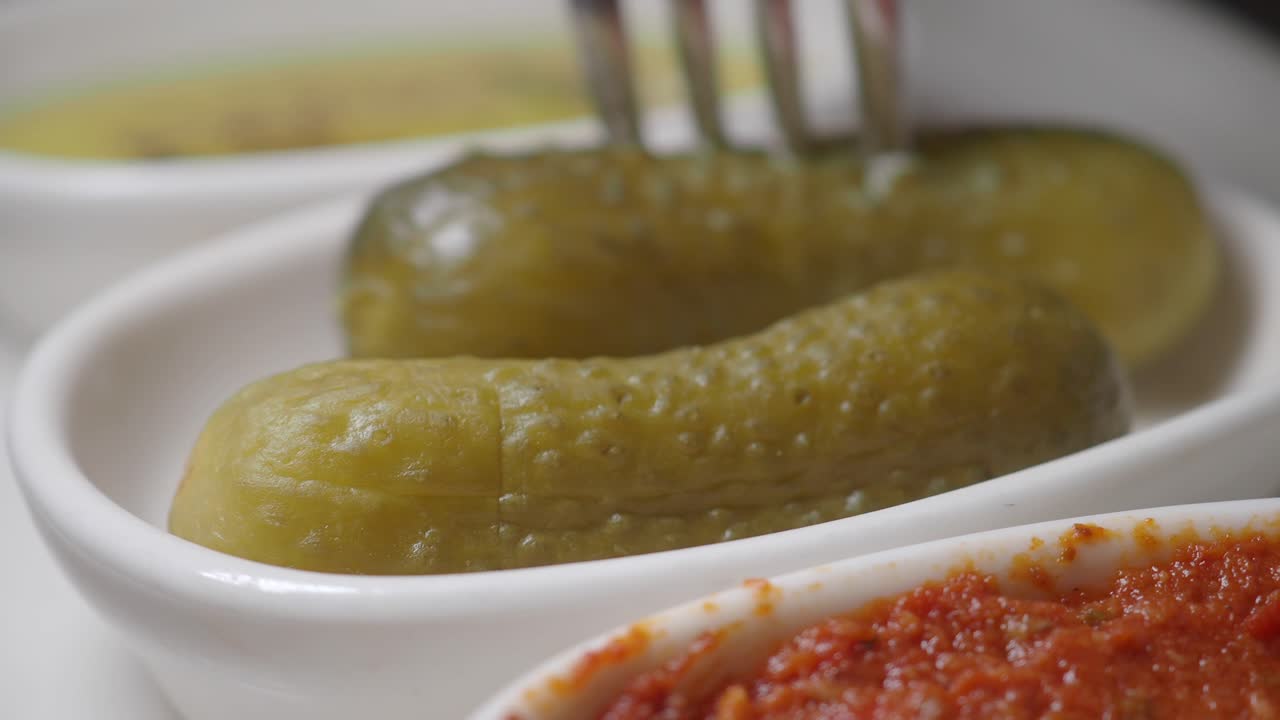 Forchetta che prende un cetriolo sottaceto da un piatto